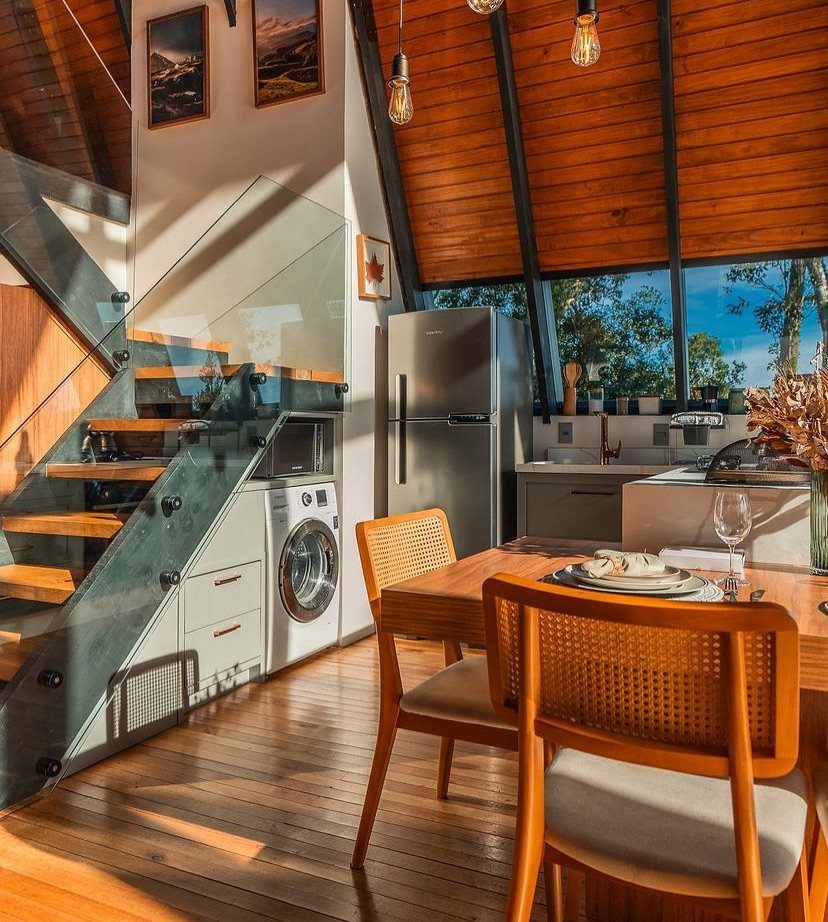 Wooden interior of an A-frame home featuring a dining area and compact kitchen.