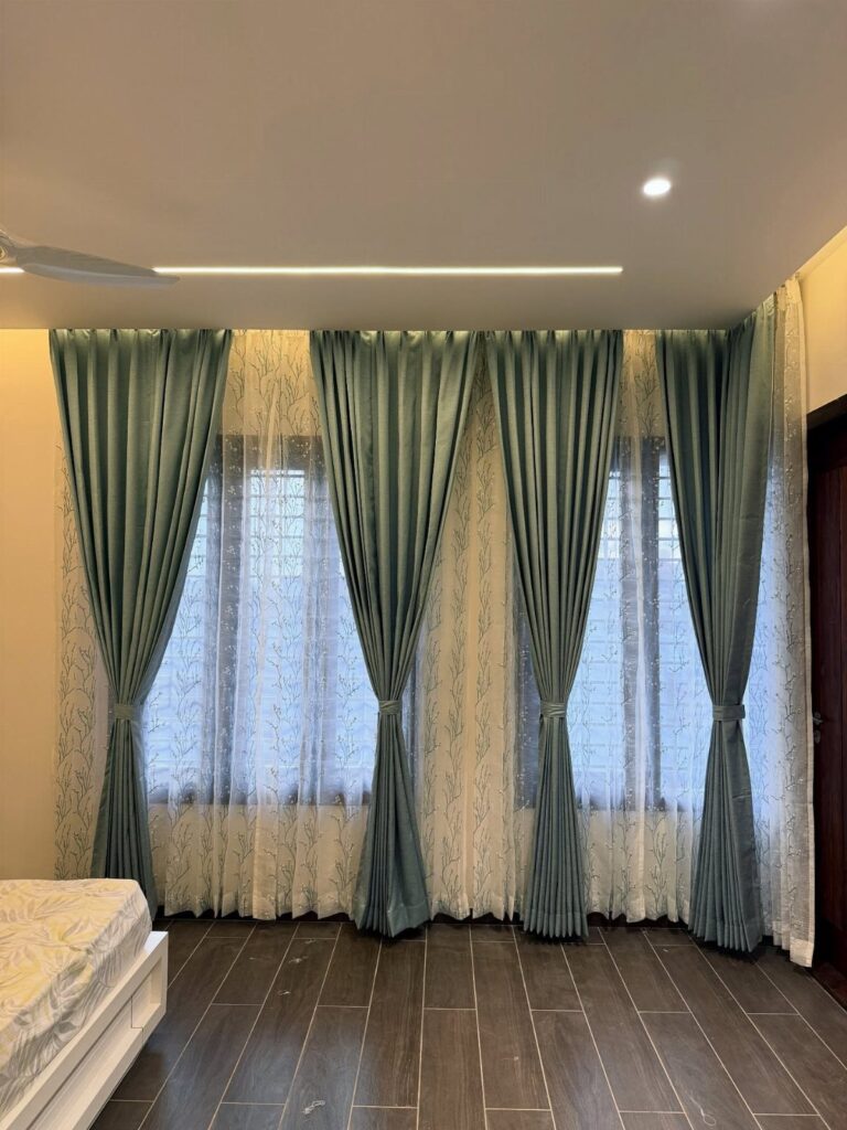 Teal curtain panels layered over white sheer lace curtains on large windows.