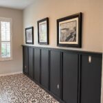 Dark grey board and batten wall paneling in a hallway with patterned tile floors.