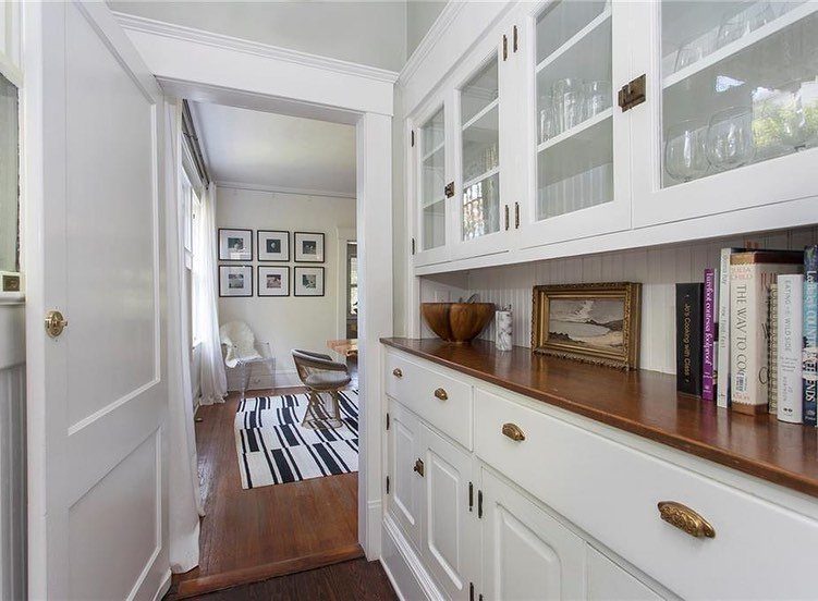 White built-in cabinets with wooden countertops leading into a bright, minimalist living room.