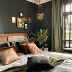 Olive green curtains and walls in a bedroom with a wooden bed.