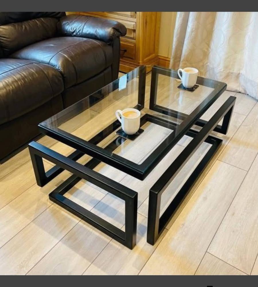 Glass top coffee table with black metal legs on a light wood floor