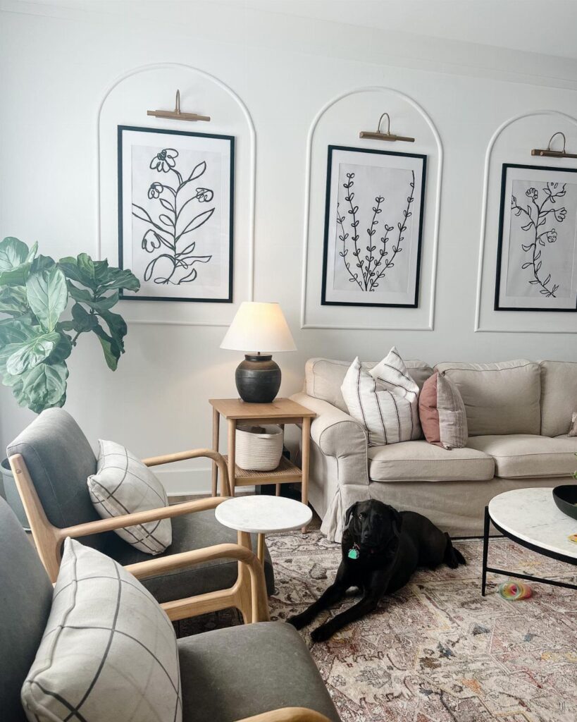 Three framed botanical prints inside wall arches decorating a large white living room wall.