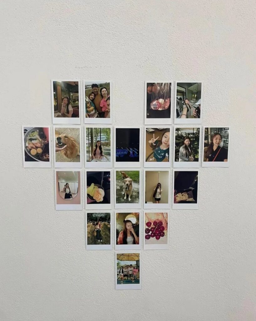Polaroid photographs arranged in a heart shape on a white textured wall.