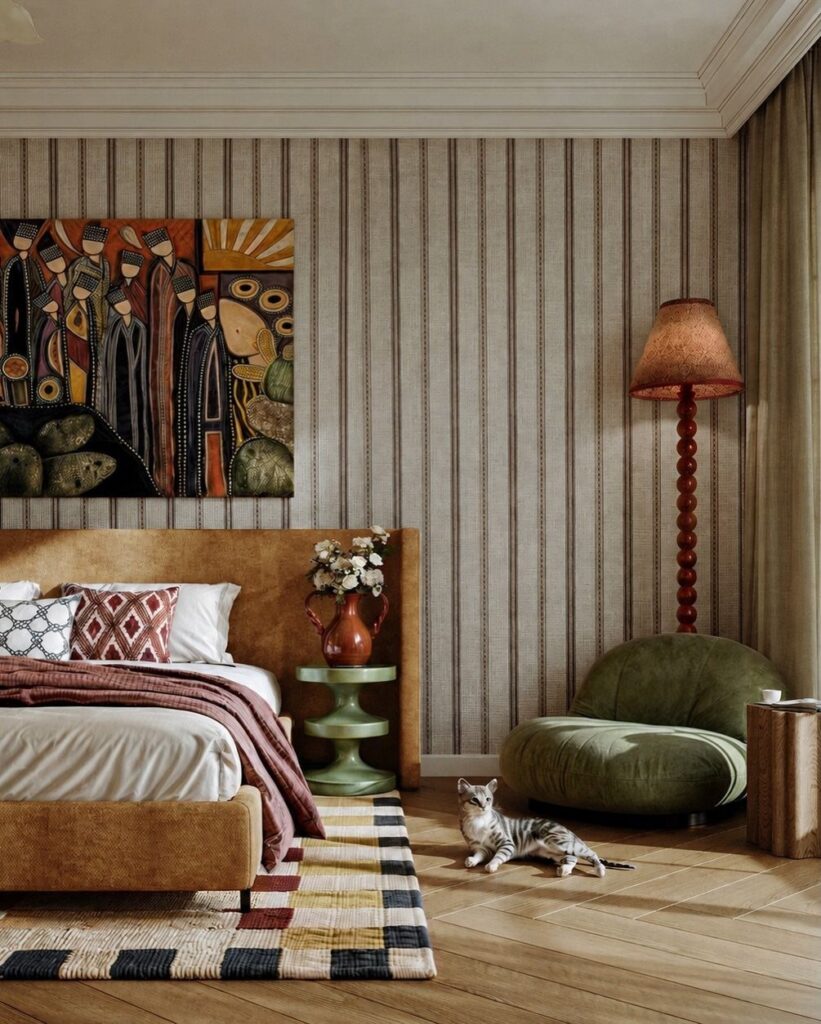 Olive green lounge chair in a bedroom with tan furniture and striped wallpaper