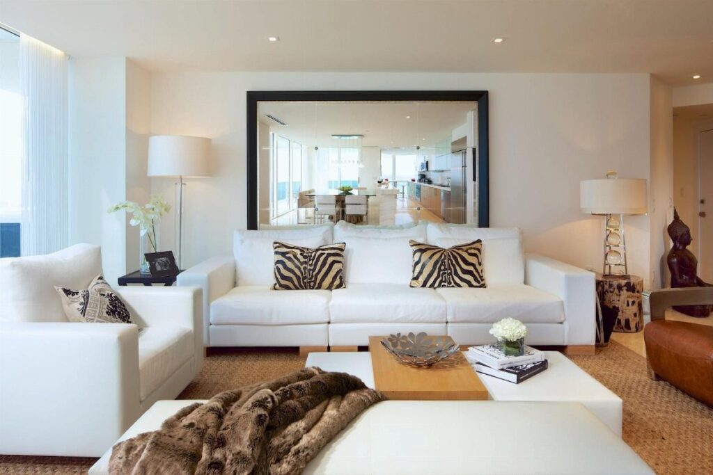 Large rectangular mirror with black frame hanging above a white modern sofa.