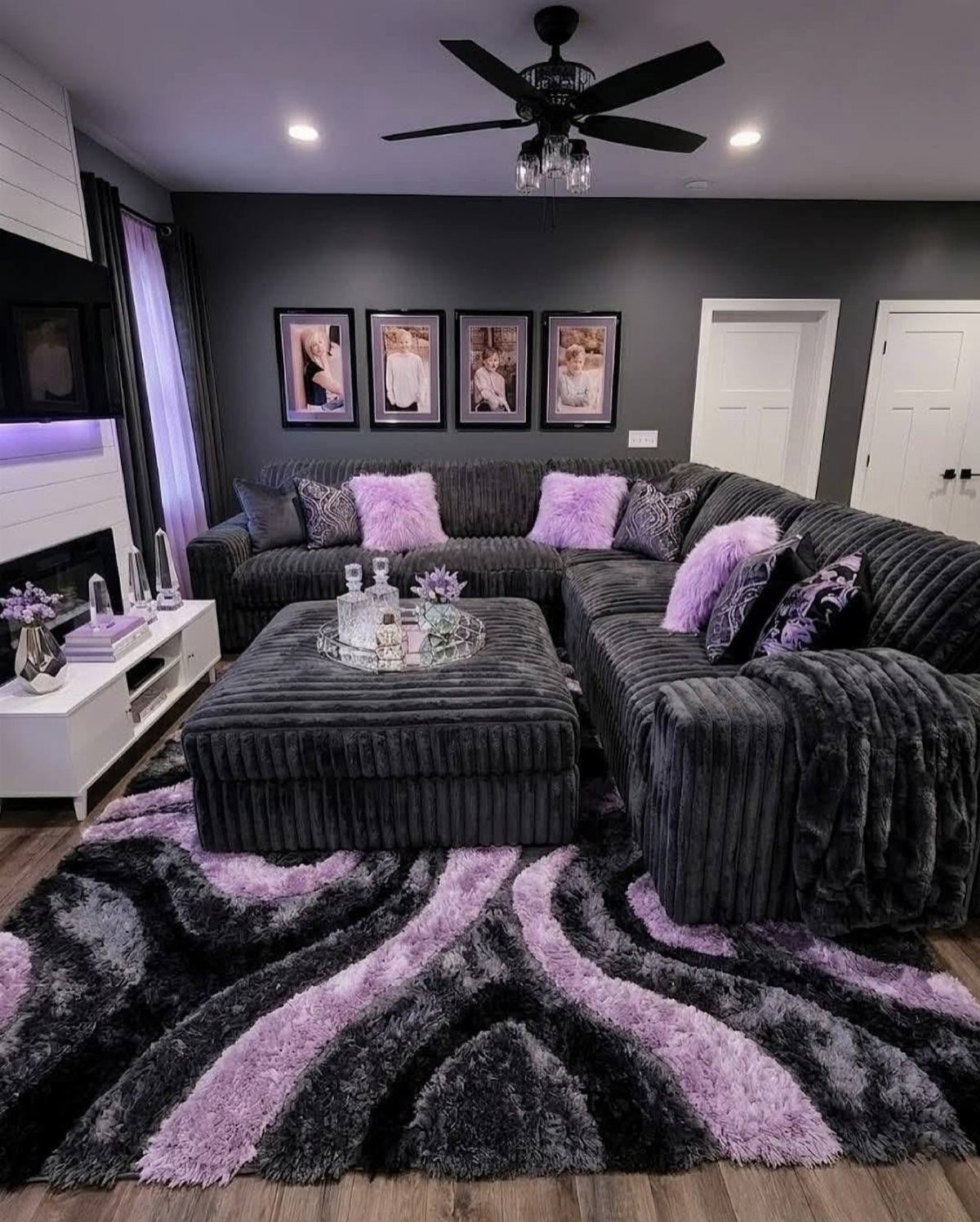 Grey sectional sofa and ottoman on a purple and grey swirl shaggy rug.