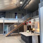 Modern industrial interior with corrugated metal ceiling, kitchen island, and loft staircase.