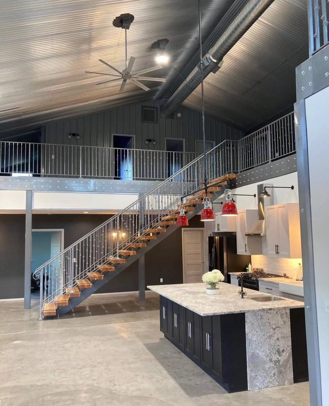 Modern industrial interior with corrugated metal ceiling, kitchen island, and loft staircase.